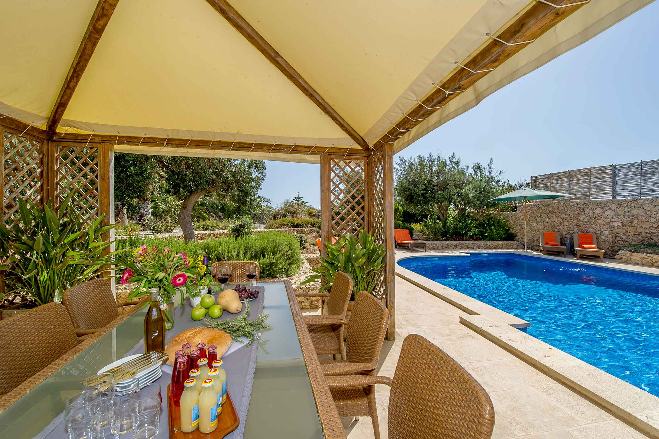 Überdachter Sitzbereich neben dem Pool in einem mediterranen Garten
